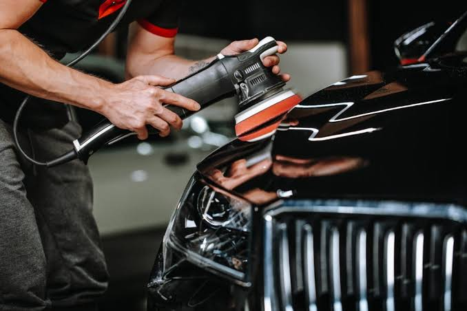 Detailer machine-polishing black paint before ceramic coating